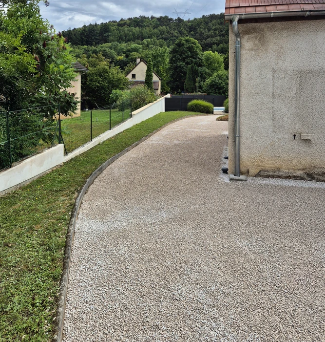 Allée résidentielle en béton désactivé avec bordures courbes, située dans un environnement pavillonnaire verdoyant