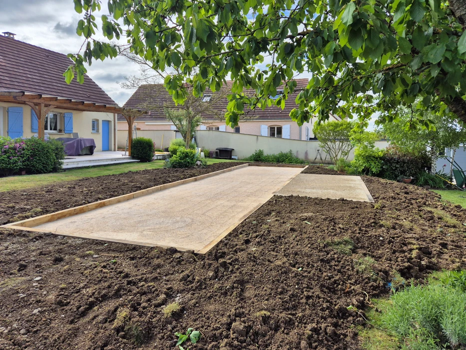 Extérieur résidentiel, allée goudronnée fraîchement revêtue devant maison en pierre naturelle beige