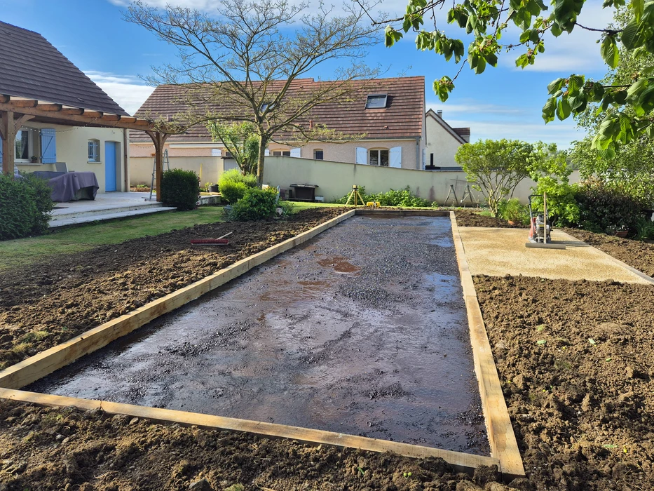 Extérieur résidentiel, allée goudronnée fraîchement revêtue devant maison en pierre naturelle beige