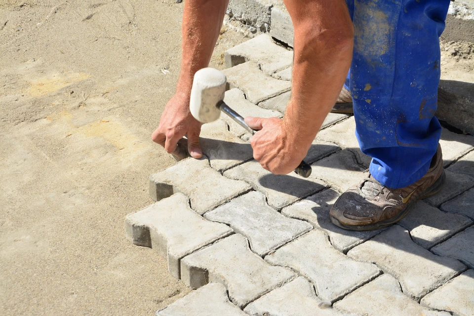 Travailleur qualifié de maçonnerie posant des briques dans un projet de construction sous la lumière du soleil sur un chantier de construction
