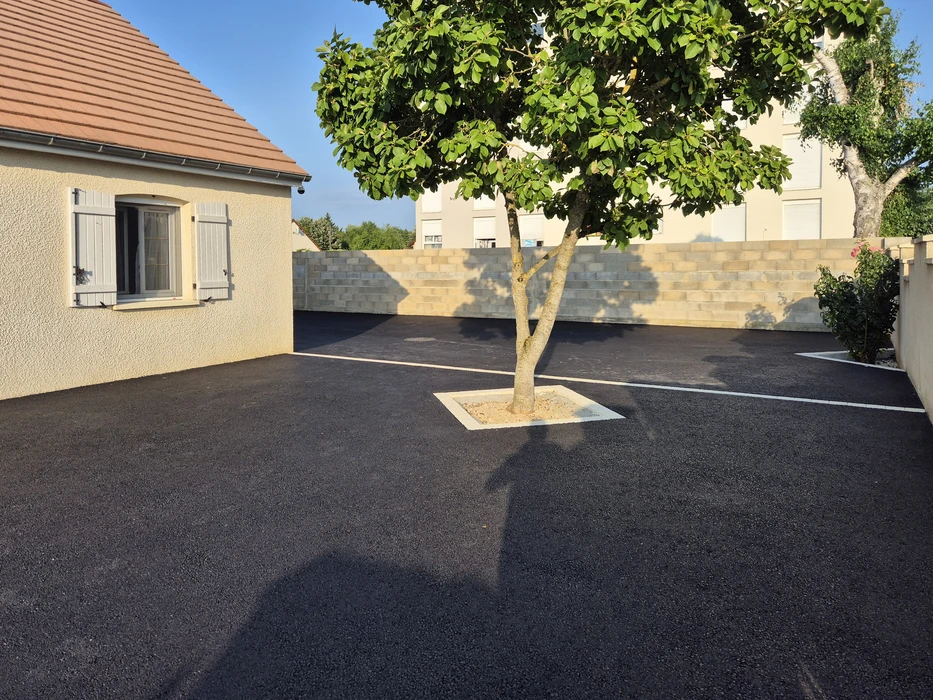 Aménagement extérieur résidentiel avec allée en gravier beige fraîchement posée, bordée de planches en bois