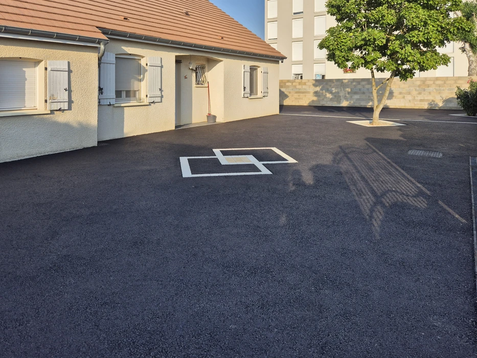 Allée d'accès résidentielle en gravier avec bordures béton dégradées, envahie par végétation spontanée