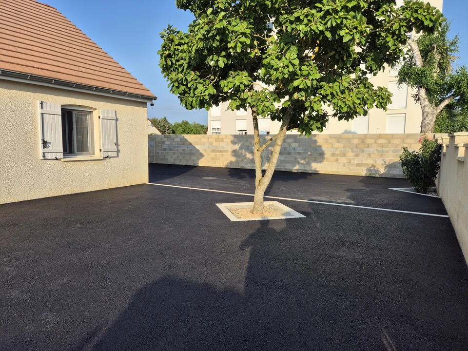 Une main gantée de jaune tient une brosse à poils durs pour nettoyer une surface en béton tachée et sale