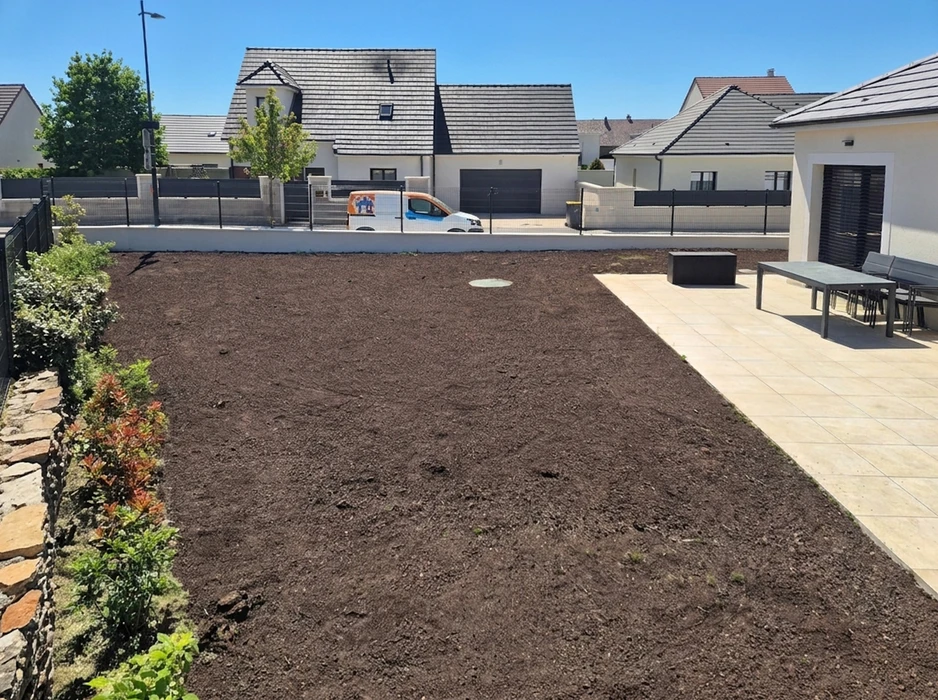 Extérieur résidentiel, allée goudronnée fraîchement revêtue devant maison en pierre naturelle beige